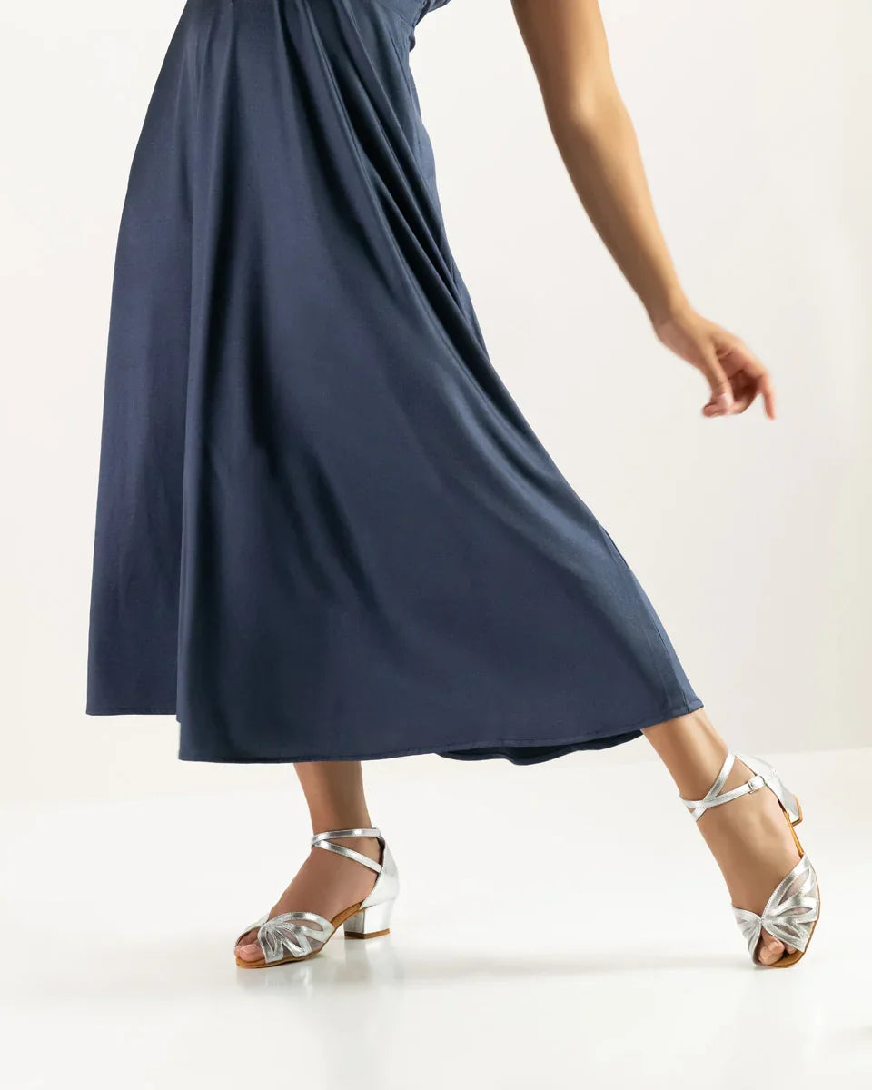 Elegante dansschoen Fabienne met zilveren details, gedragen bij een lange blauwe jurk.