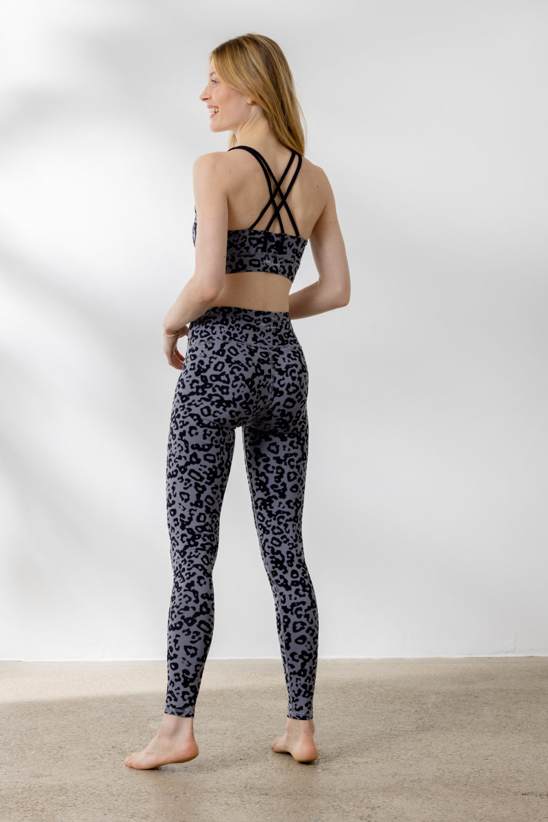 Model showcasing Hey Honey Criss-Cross Bra and leggings with Distorted Animal print from the back, perfect for yoga and fitness.