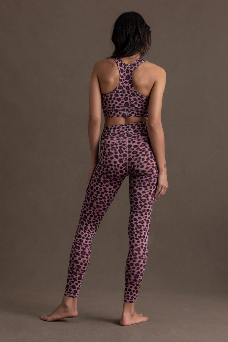 Model wearing Hey Honey Yoga Bra Leo Rose with leopard print design, showcasing racerback and leggings in soft rose color.