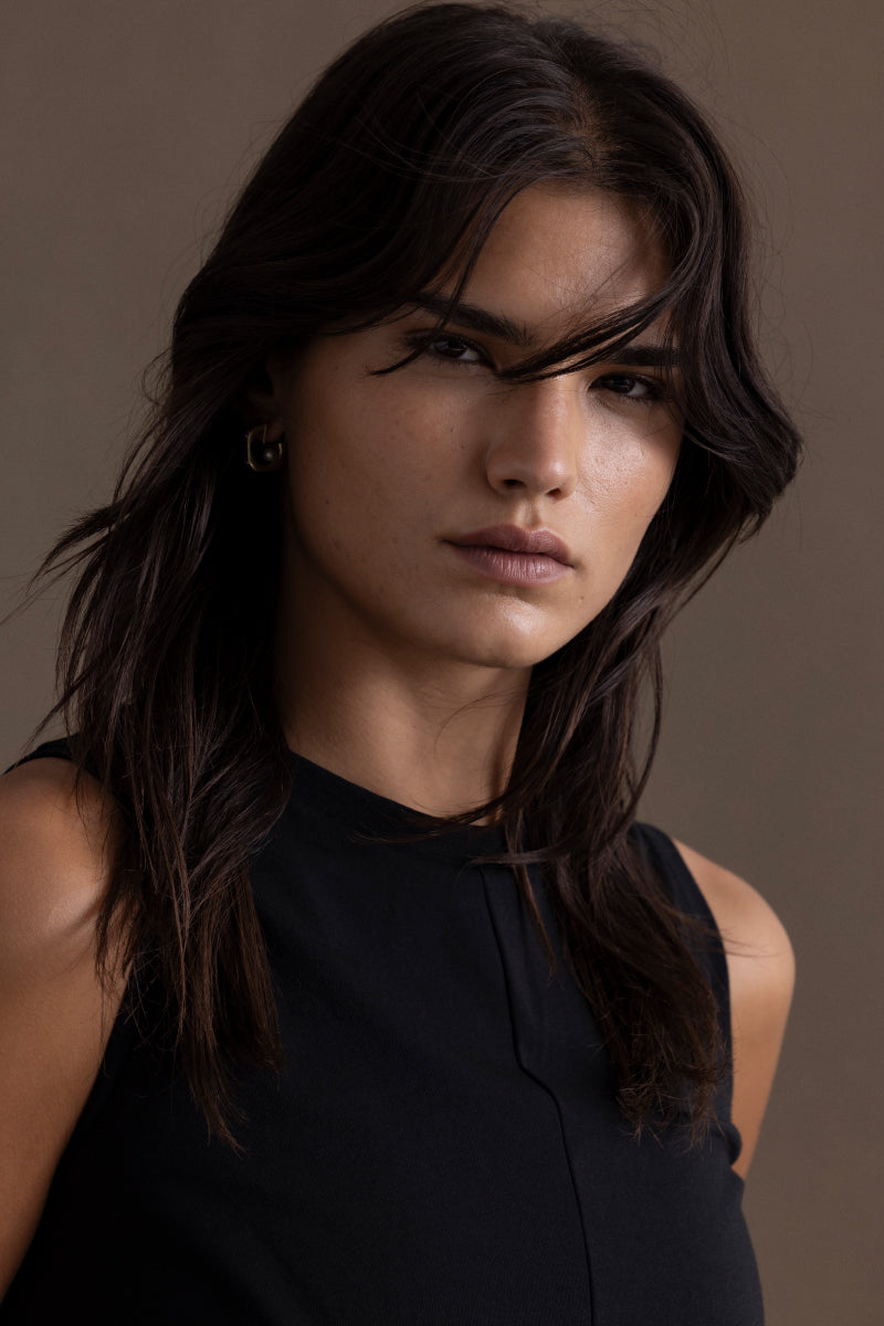 Model wearing a cropped black top, showcasing a stylish and casual look with natural makeup and tousled hair.