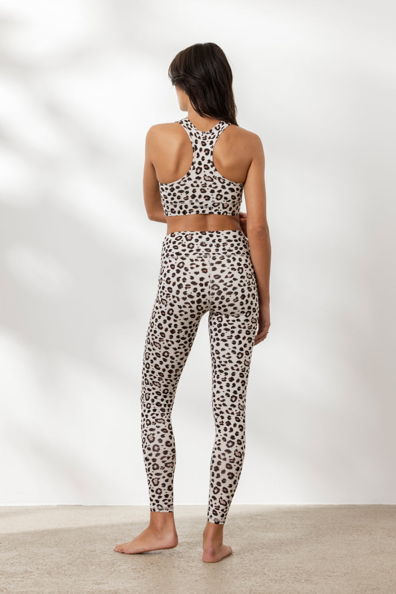 Back view of a woman in a leopard print yoga outfit featuring a racerback top and matching leggings.