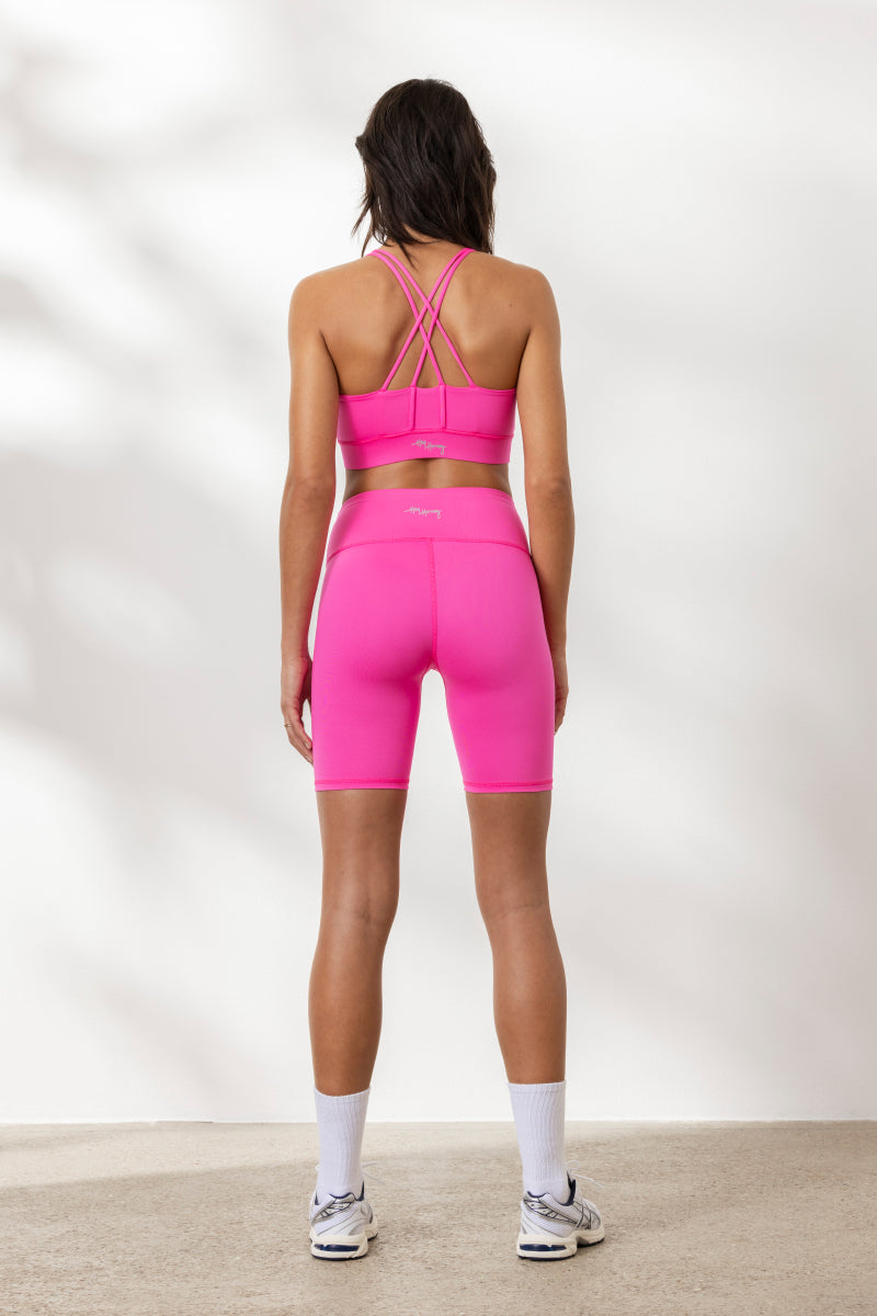 Back view of a model wearing Hey Honey Yoga Biker Neon Pink set, featuring a high waist design in vibrant neon pink.