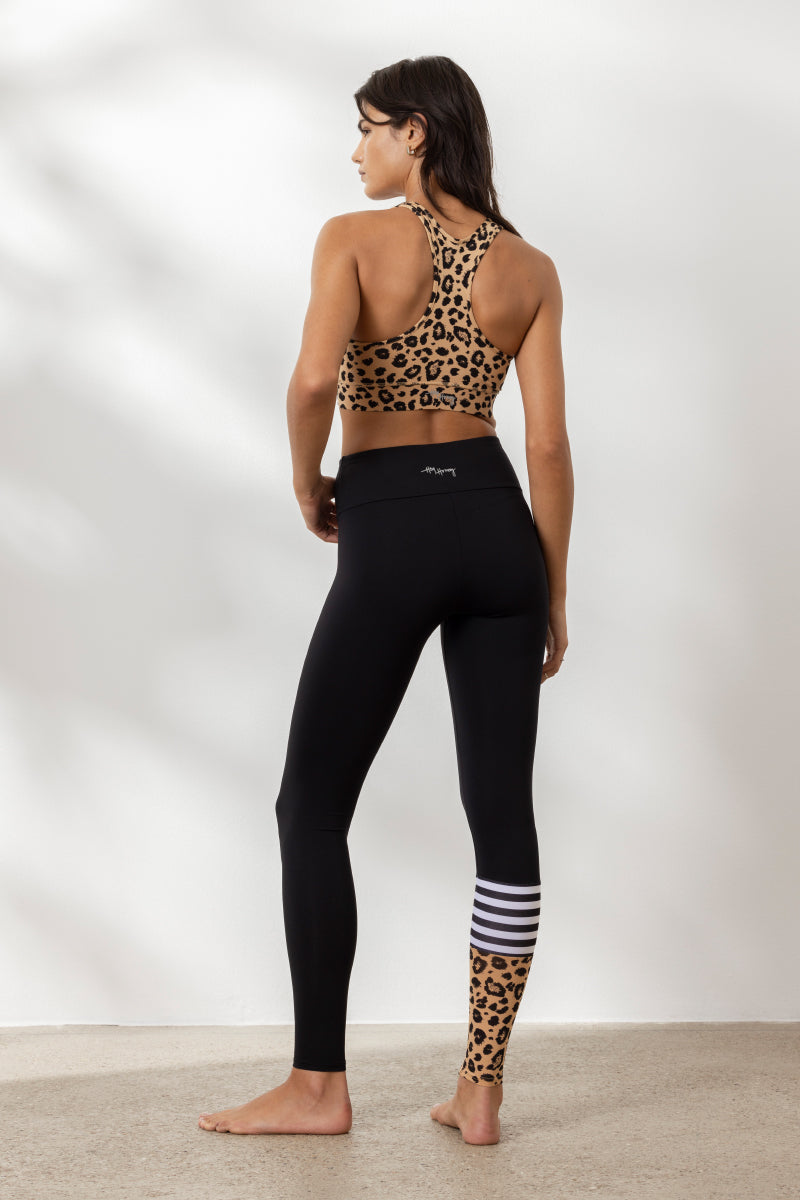 Woman in leopard print sports bra and black leggings, showcasing stylish yoga wear from Hey Honey.