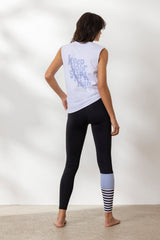 Woman in a sleeveless white tank top with "Keep Your Spirit High" text, paired with black leggings and yoga attire.
