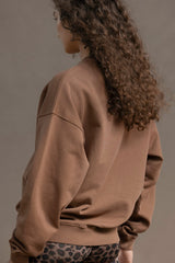 Model showcasing the Trui Cacao sweater, a cozy brown cotton pullover with a relaxed fit, perfect for casual wear.