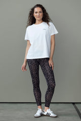 Model wearing a white T-shirt with black leggings, showcasing a casual and sporty outfit style.