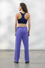Woman wearing a black floral sports bra and violet Trackpant PHOENIX, showcasing a relaxed fit from the back.