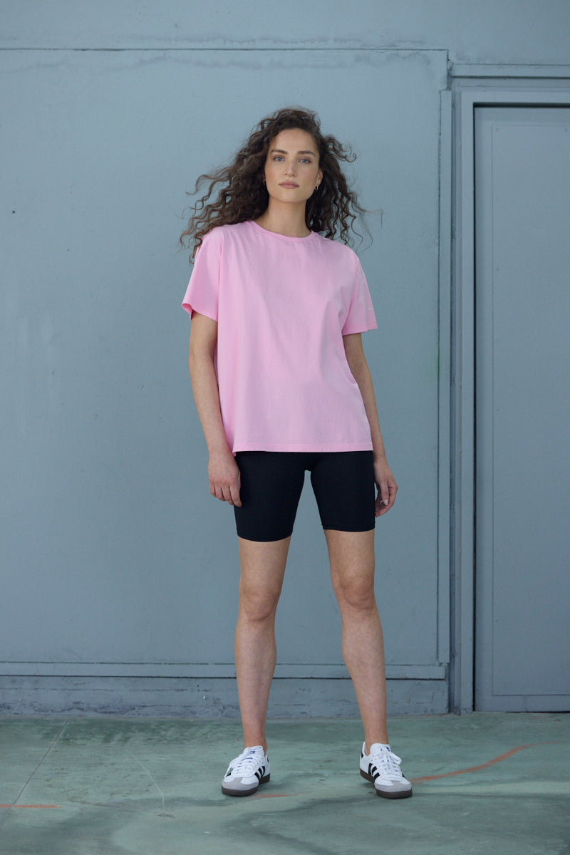 Model wearing a comfortable pink T-shirt with black shorts, showcasing a stylish casual look for everyday wear.