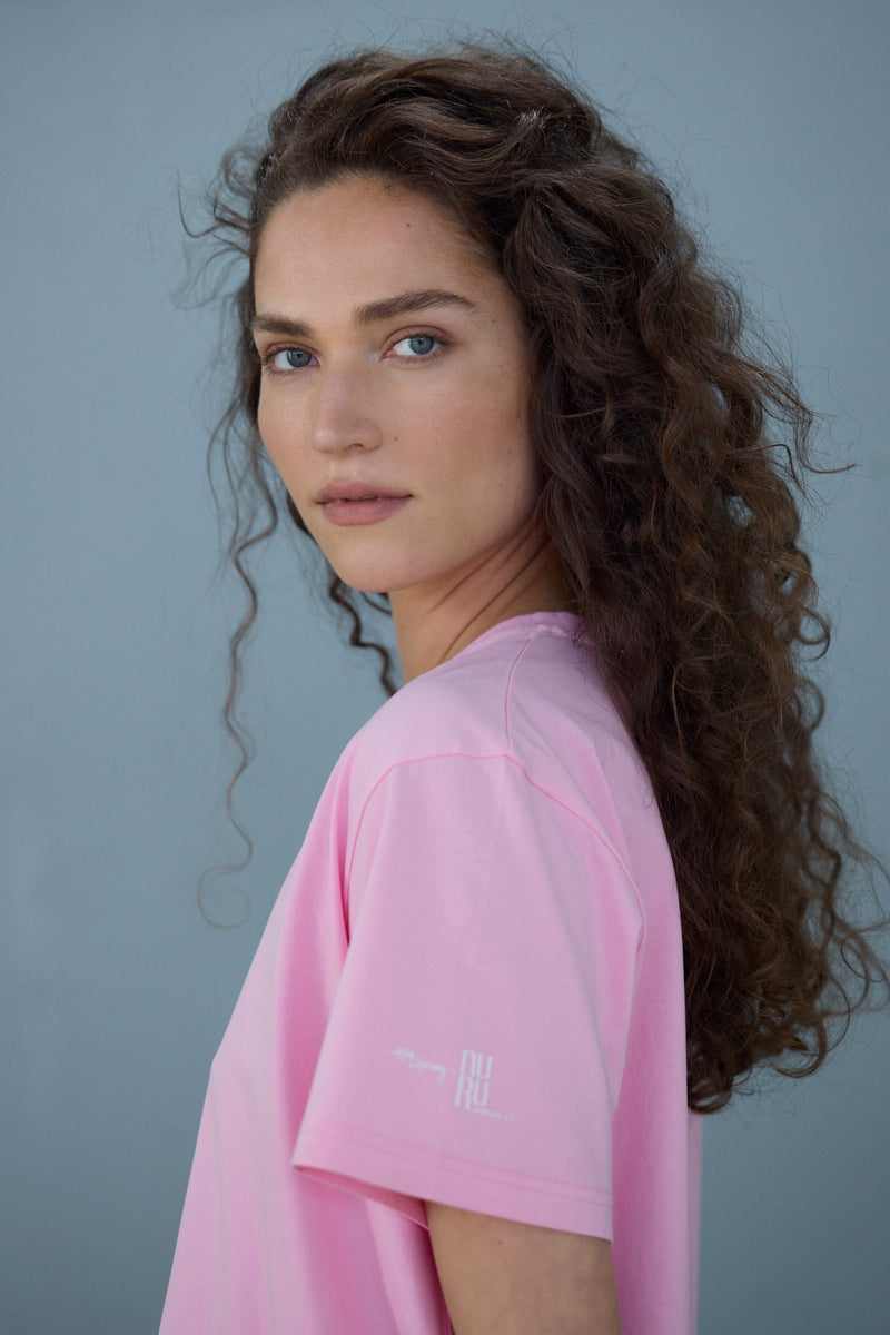 Model showcasing a pink T-shirt with elegant "Mother" text, highlighting its casual and stylish design.