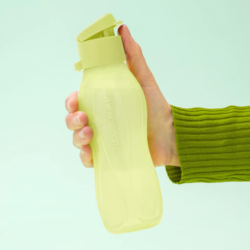 Person holding a Tupperware EcoEasy 500ml drink bottle in light green color, showcasing its ergonomic design.