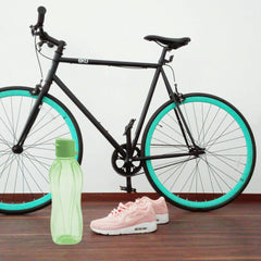 Tupperware EcoEasy 500ml water bottle beside a black bicycle and pink sneakers on a wooden floor.