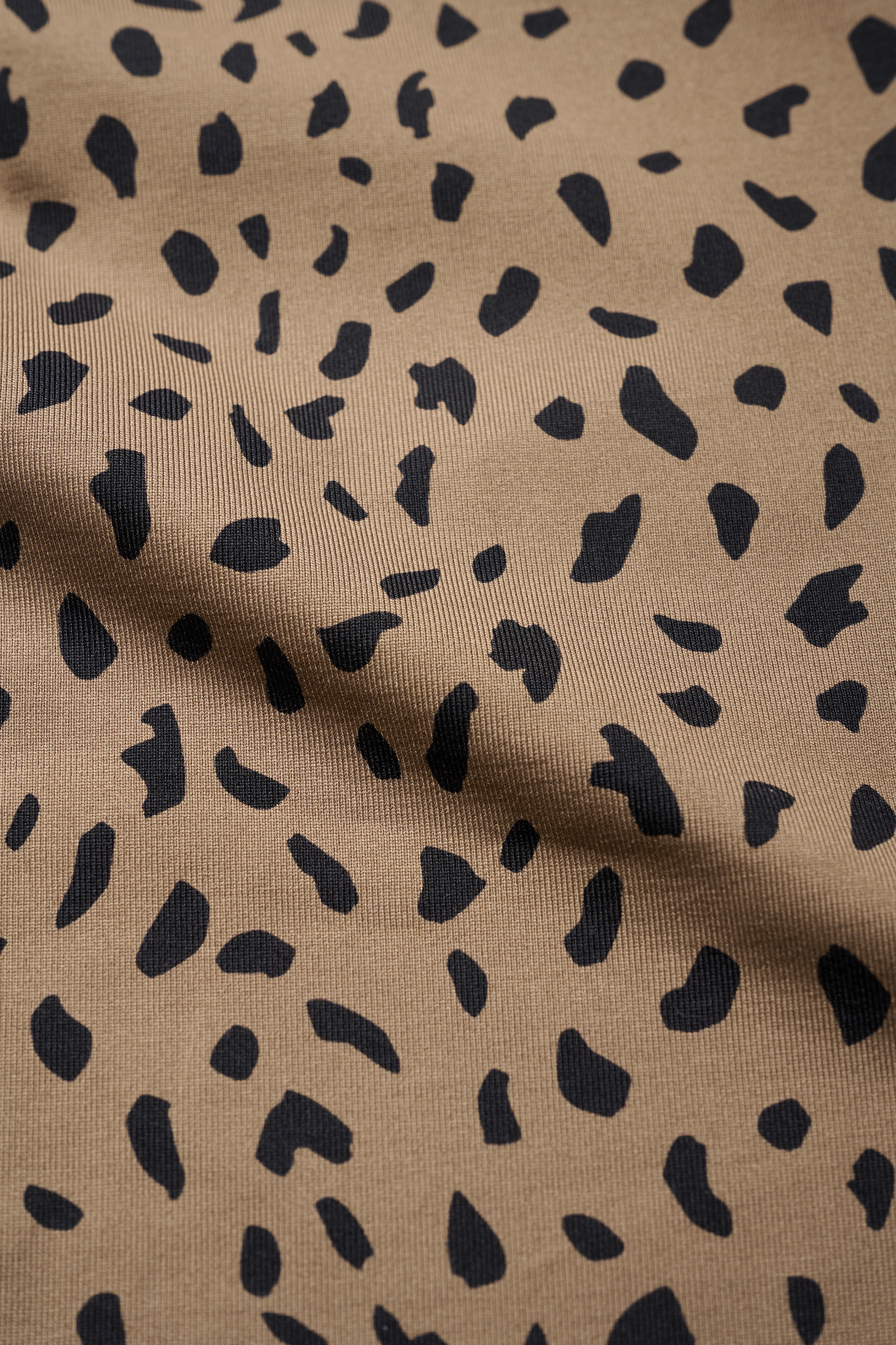 Close-up of tan fabric with black leopard print pattern ideal for stylish activewear.