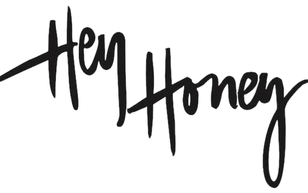 Stylish handwritten logo saying "Hey Honey" in elegant black script on a transparent background.
