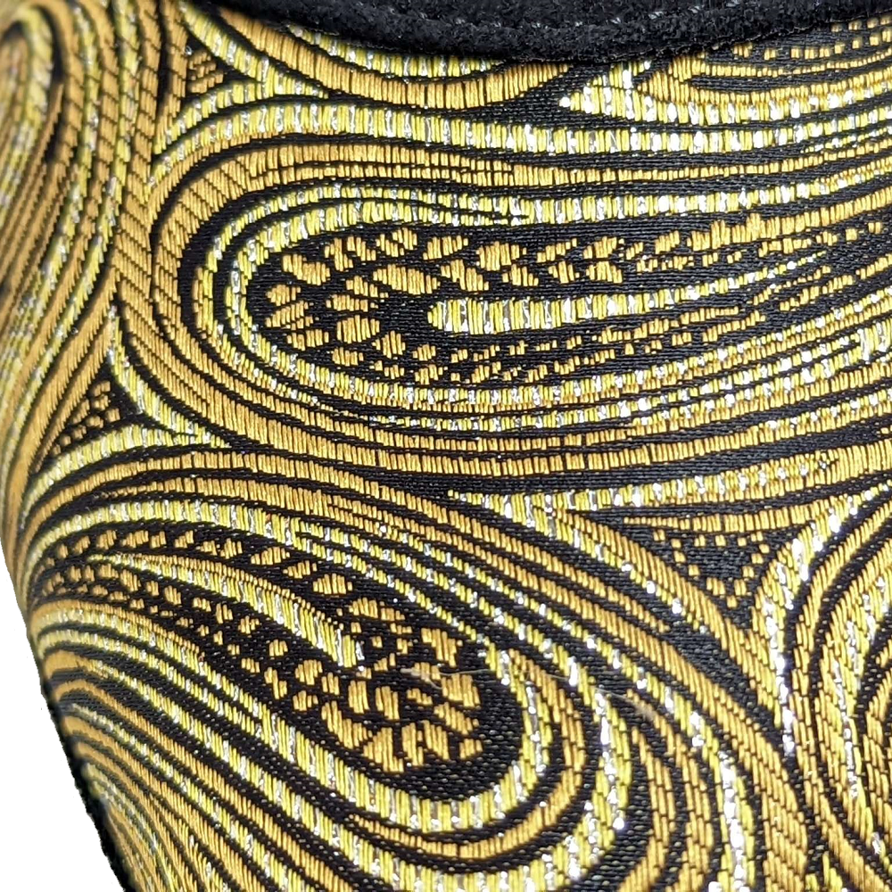 Close-up of luxurious gold and black patterned fabric, showcasing intricate swirls and textures perfect for stylish footwear.